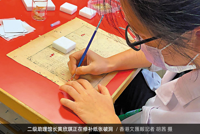 香港中央圖書館二級助理館長黃欣琪正在修補紙張破洞/香港文匯報記者 胡茜 攝